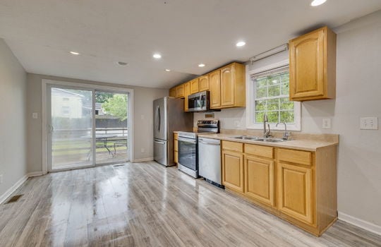 kitchen, laminate flooring, recessed lighting, cabinets, countertops, sink, dishwasher, range, built-in microwave, refrigerator, sliding door to side porch, window