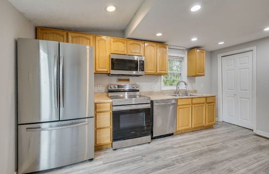 Kitchen, stainless appliances, refrigerator, range, dishwasher, cabinets, countertops, sink, built-in microwave, recessed lighting, laminate flooring