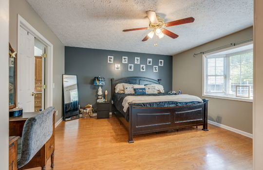 primary bedroom, hardwood flooring, ceiling fan, bay window, door to primary bath