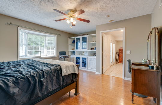 primary bedroom, built-in shelving, bay window, ceiling fan, hardwood flooring