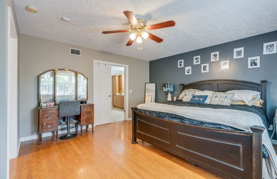primary bedroom, hardwood flooring, ceiling fan, door to primary bathroom