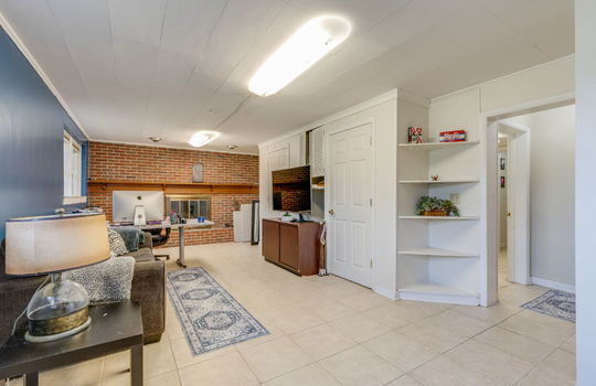 den, brick fireplace wall, windows, built-in shelving, storage closets, tile flooring