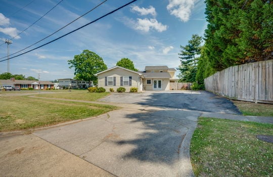 side view of home, driveway, side yard, landscaping, fencing, exterior doors