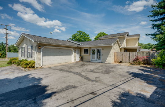 driveway, two car garage, exterior entry doors, fencing, landscaping