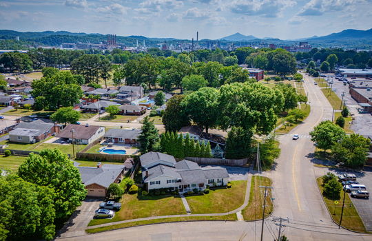 aerial photo, tri-level home, front yard, back yard, driveway, sidewalk, road, neighboring homes, mountains