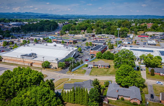 aerial photo, tri-level home, front yard, back yard, driveway, sidewalk, road, neighboring homes, mountains, shopping areas