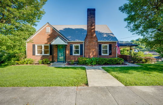 Brick, cottage, covered front porch, sidewalk, metal roof, front yard, trees, landscaping