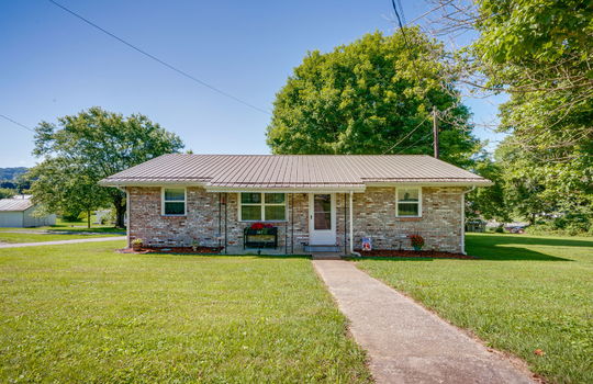 brick, ranch style home, sidewalk, front yard, covered front porch, front door, metal roof