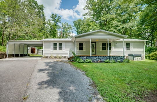 Double wide, vinyl siding, covered front porch, driveway, carport, front yard, trees