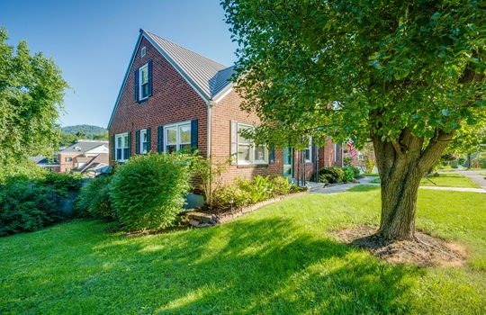 front left side view of home, cottage, brick, front door, front yard, trees, landscaping