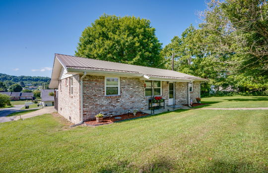 left side view of home, brick, ranch style home, front yard, sidewalk, front door, covered front porch, metal roof