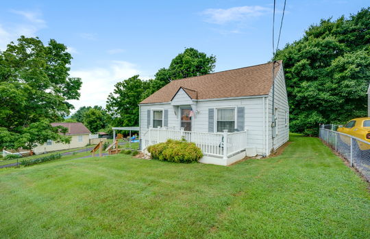 right side view of home, one story cottage, front porch, front door, side yard, front yard, trees, vinyl siding, shingle roof