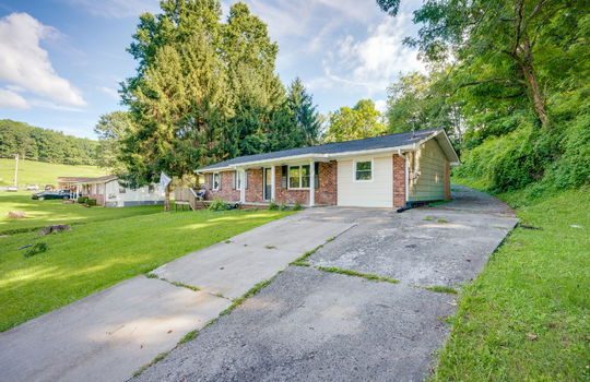 right side view of home, concrete driveway, brick ranch, covered front porch, front door, front yard, neighboring home, trees