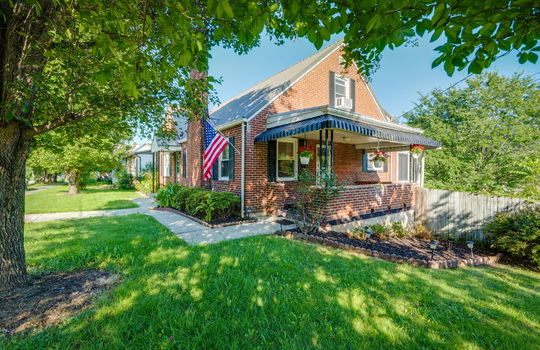 right side view of home, cottage, traditional home, brick, carport, landscaping, trees, front porch, front door, side door