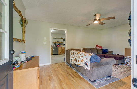 living room view from front door, hardwood flooring, ceiling fan, doorway to kitchen
