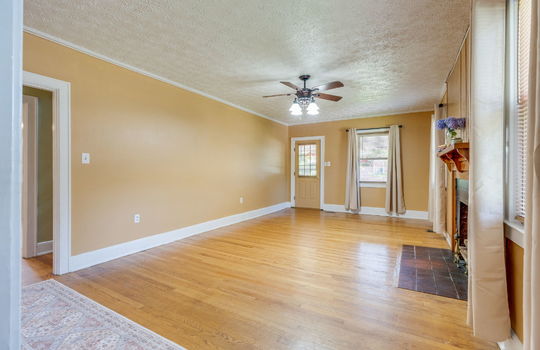 living room, hardwood flooring, exterior door, ceiling fan, fireplace, windows