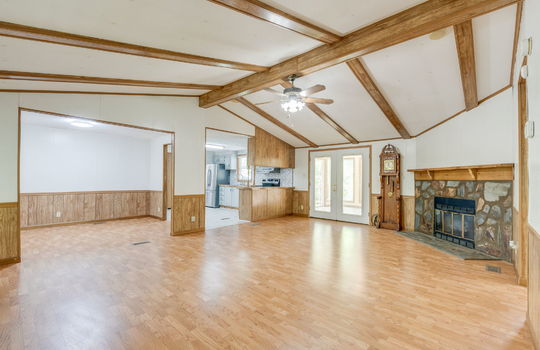 living room, ceiling fan, fireplace, double doors, doorway to kitchen, doorway to dining area, ceiling with beams