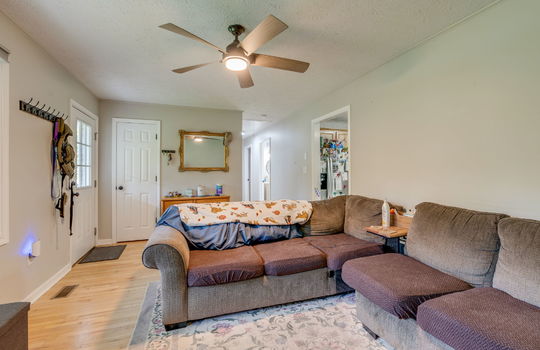 living room, front door, entry closet, ceiling fan, hardwood flooring, doorway to kitchen, hallway