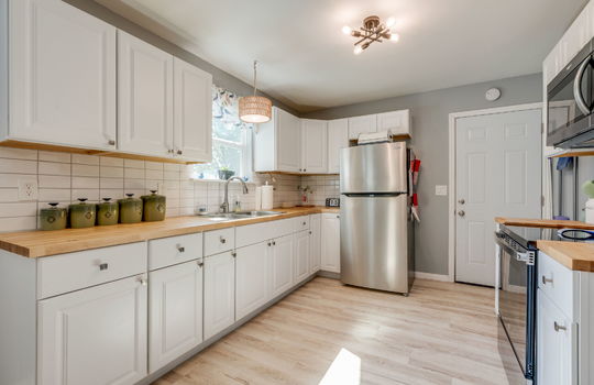 kitchen, butcher block countertops, cabinets, stainless appliances, refrigerator, built-in microwave, electric range, tile backsplash, luxury vinyl flooring, sink, window above sink