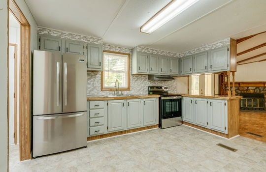 kitchen, refrigerator, electric range, cabinets, countertops, tile backsplash, sink, window above sink, vinyl flooring