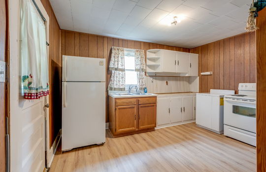 kitchen, exterior door, countertops, sink, window above sink, cabinets, refrigerator, electric range, paneling walls, laminate flooring