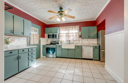 kitchen, tile flooring, stainless appliances, refrigerator, dishwasher, apron sink, electric range, built-in microwave, cabinets, countertops, ceiling fan, window, exterior door