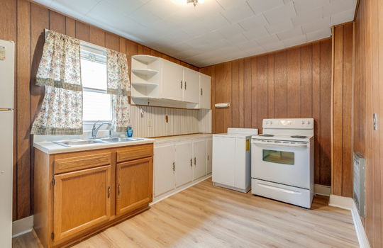 kitchen, sink, cabinets, countertops, paneling walls, laminate flooring, electric range, window above sink