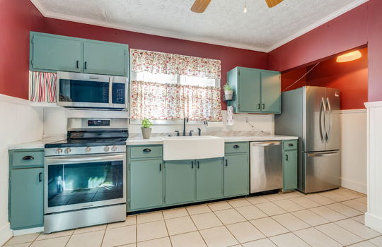 kitchen, tile flooring, stainless appliances, refrigerator, dishwasher, apron sink, electric range, built-in microwave, cabinets, countertops, ceiling fan, window