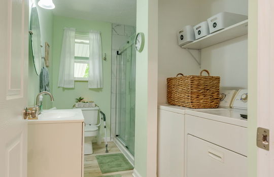 bathroom, laundry area, sink, toilet, tile shower, glass shower door, luxury vinyl flooring
