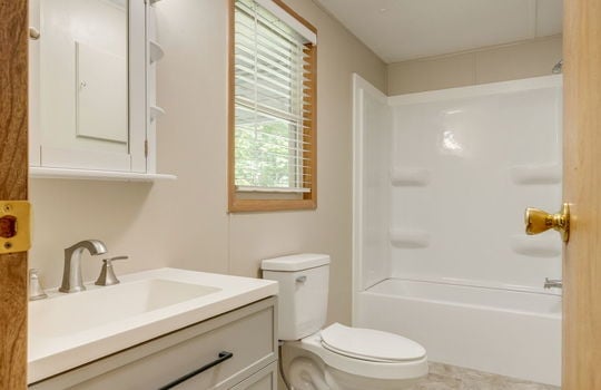 primary bathroom, sink, toilet, shower/tub, window, vinyl flooring