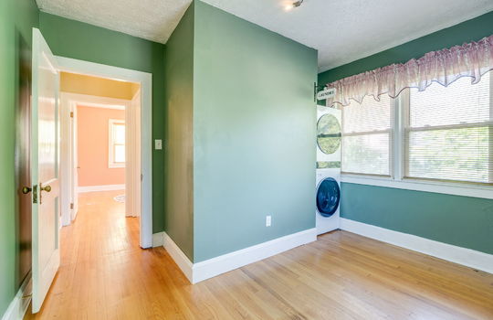 bedcroom, laundry space, hardwood flooring, windows, door, hallway