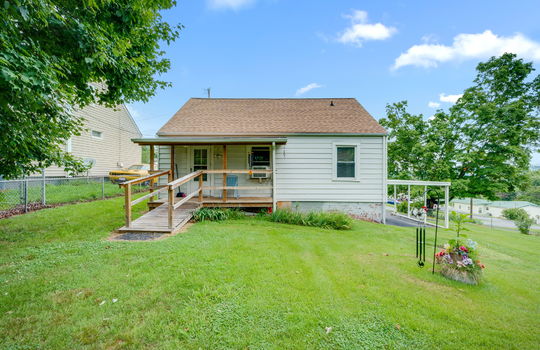 023back yard, back view of home, carport, back porch, covered back porch, ramp, exterior door, cottage, vinyl siding, driveway