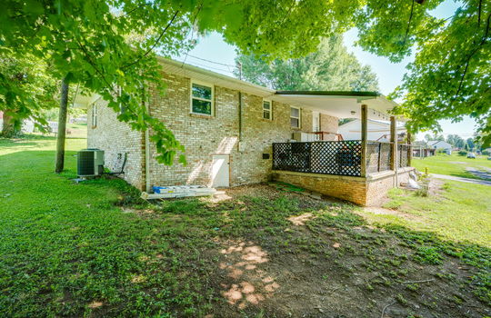 back of home, brick, ranch style home, parking pad, covered back porch, exterior door, back yard