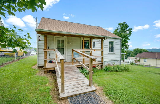 023back yard, back view of home, carport, back porch, covered back porch, ramp, exterior door, cottage, vinyl siding, driveway