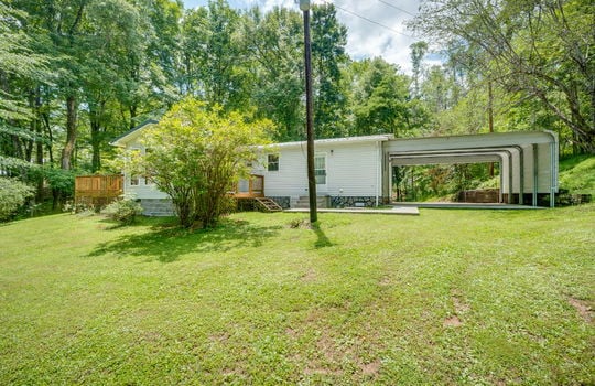 back of home, landscaping, exterior doors, sets, carport, vinyl siding, metal roof, back deck, back yard, trees