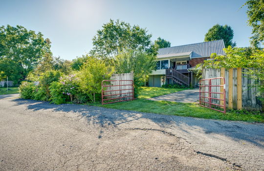 driveway gate, driveway, back of home, fencing, stairs to back porch, sunroom