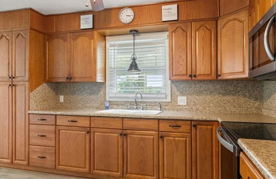 kitchen, built-in microwave, oven/range, sink, window above sink, countertops, cabinets