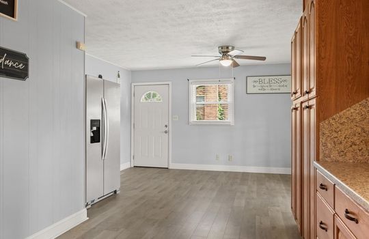kitchen view into dining area, cabinets, countertops, refrigerator, exterior door, ceiling fan