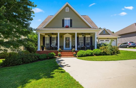 house, covered front porch, sidewalk, stairs to front porch, front door, garage, yard, landscaping, vinyl siding, shingle roof