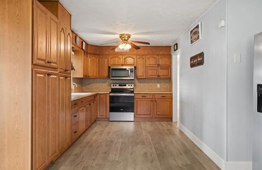 kitchen, cabinets, countertops, oven/range, built in microwave, sink, ceiling fan, luxury vinyl flooring