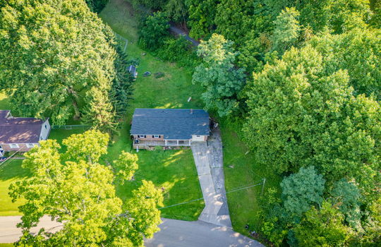 aerial view of home, road, concrete driveway, roof, front yard, back yard, storage shed, trees, neighboring homes