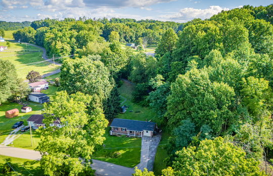 aerial view of home, road, concrete driveway, roof, front yard, back yard, storage shed, trees, neighboring homes