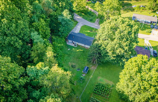 aerial view of home, road, concrete driveway, roof, front yard, back yard, storage shed, trees, neighboring homes
