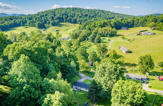 aerial view of home, road, concrete driveway, roof, front yard, back yard, storage shed, trees, neighboring homes, mountain view