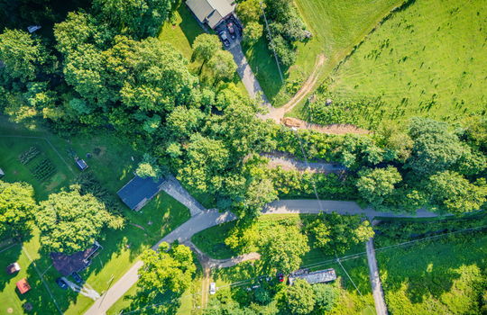 aerial view of home, road, concrete driveway, roof, front yard, back yard, storage shed, trees, neighboring homes