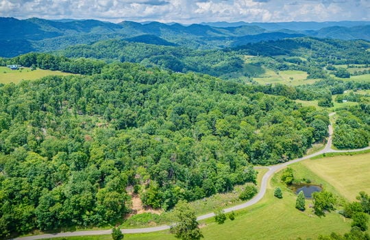 aerial view of property, surrounding properties, trees, fields, road, mountain views
