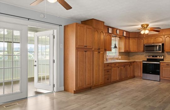 kitchen, cabinets, countertops, oven/range, built-in microwave, sink, window above sink, double doors into sun room, ceiling fans