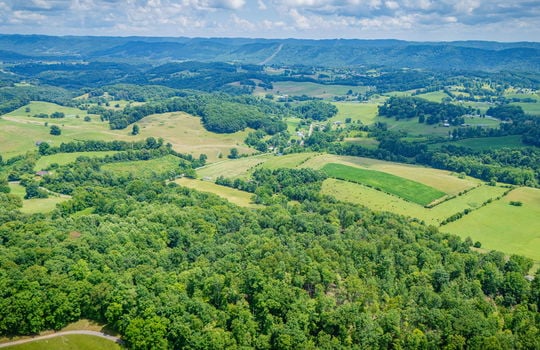 aerial view of property, surrounding properties, trees, fields, road, mountain views