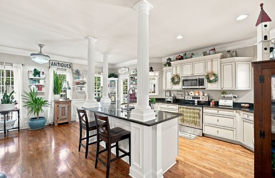 kitchen, kitchen island, stainless steel appliances, granite countertops, exterior door, sink in island, built in microwave, oven/range, recessed lighting, hardwood flooring