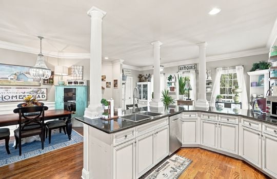 kitchen, dishwasher, cabinets, island, sink in island, granite countertops, hardwood flooring, recessed lighting, view into dining space